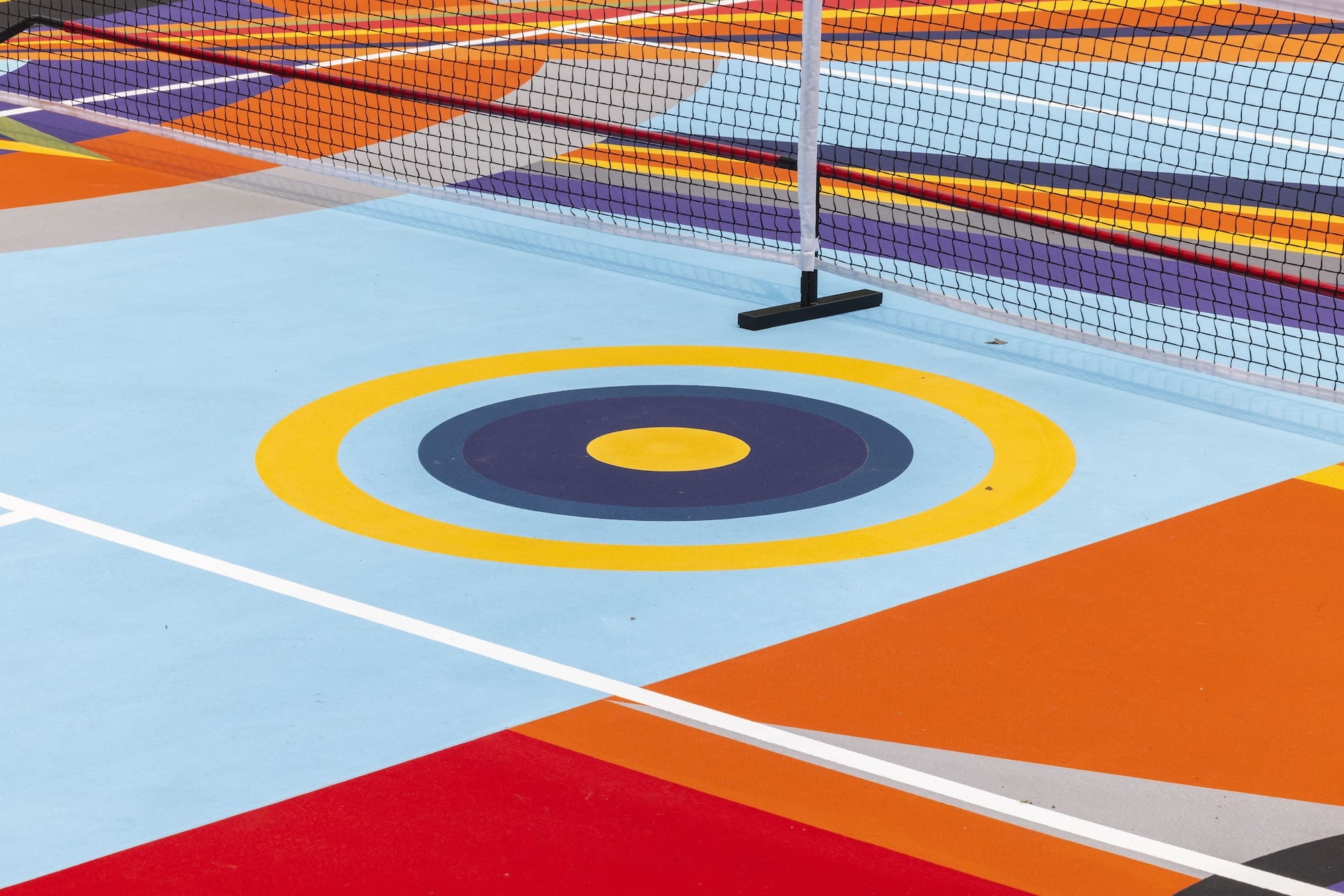 a detail of a pickleball court that has been painted with a bright geometric mural