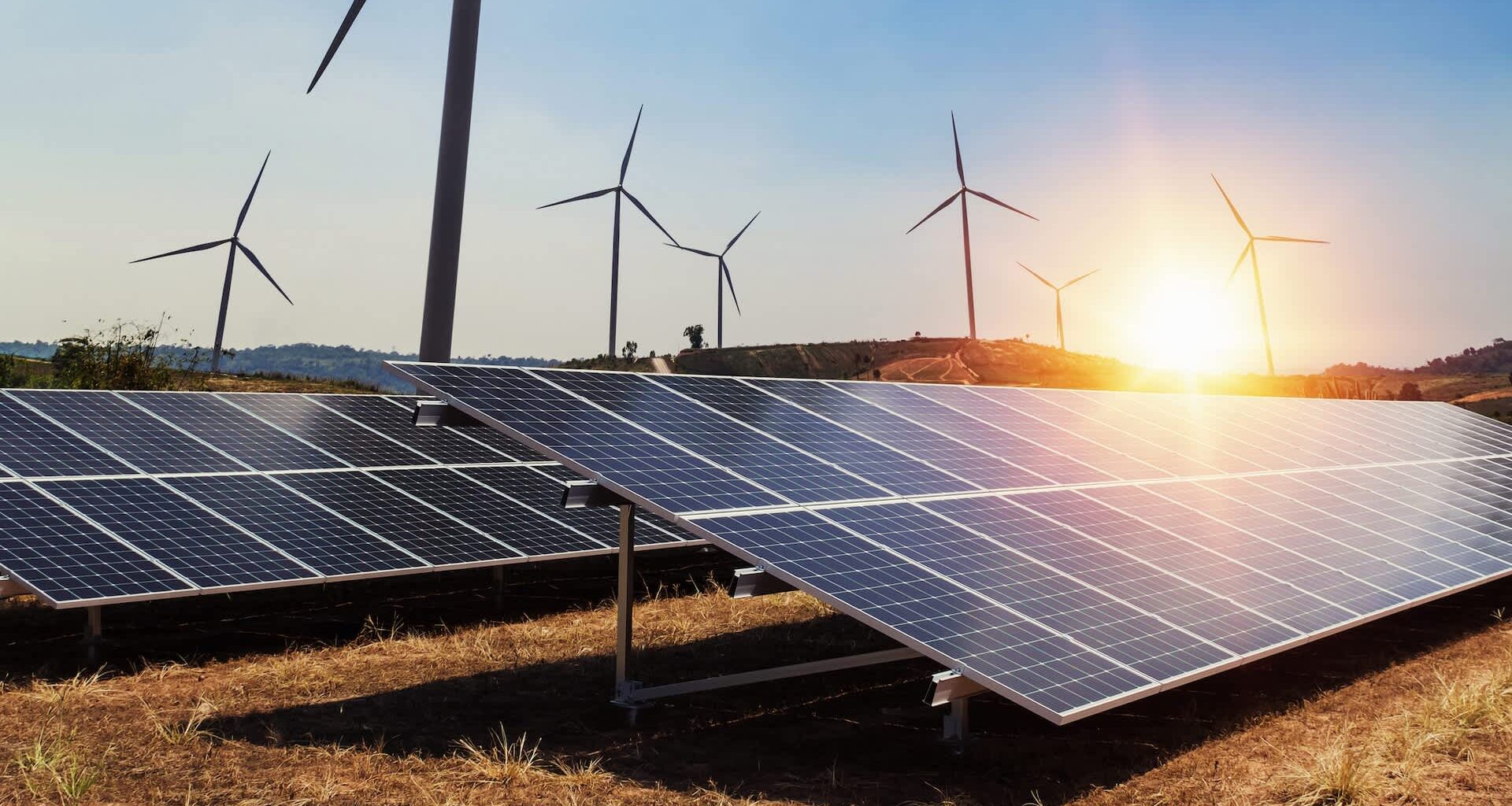 Solar panels and wind turbines at sunset.