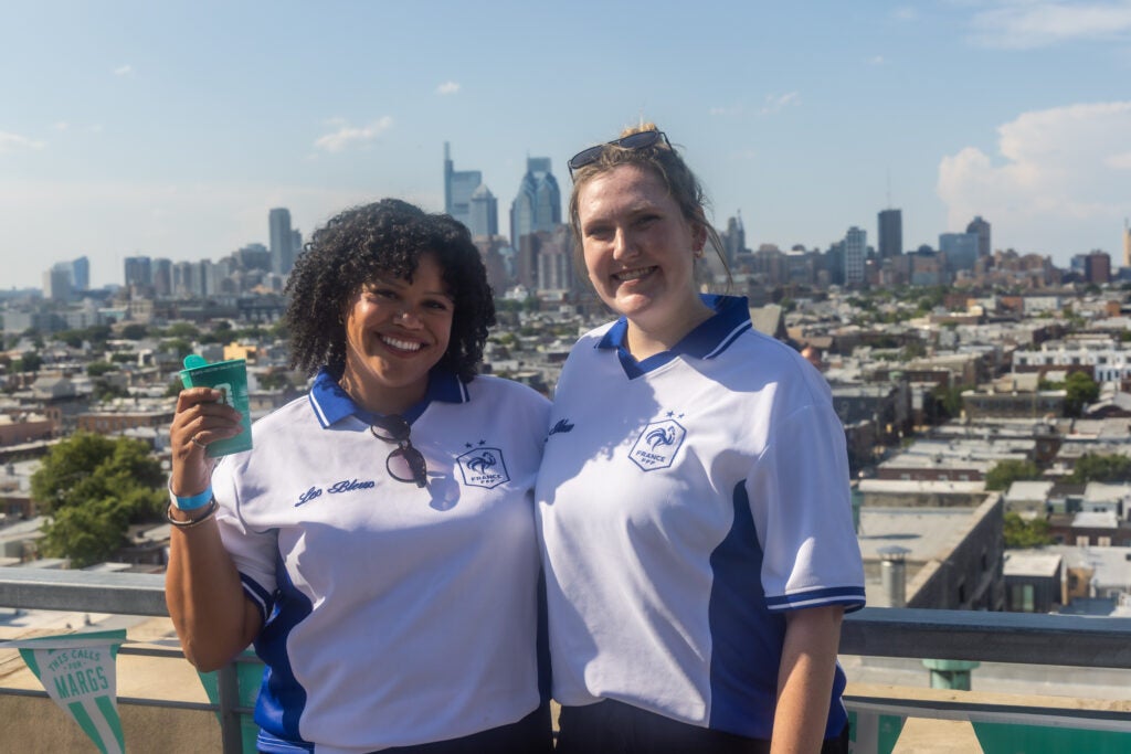 Gabrielle Swain and Ashely Boyle pose for a photo at the rooftop bar with the Philly skyline behind them.