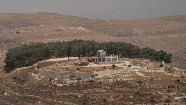 The view from St. George's Church in Taybeh include the outskirts of the town and, on the hillside in the distance, settlement building.