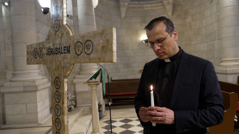 Father Munther Isaac lights a candle and prays inside the Bethlehem Christmas Lutheran Church
