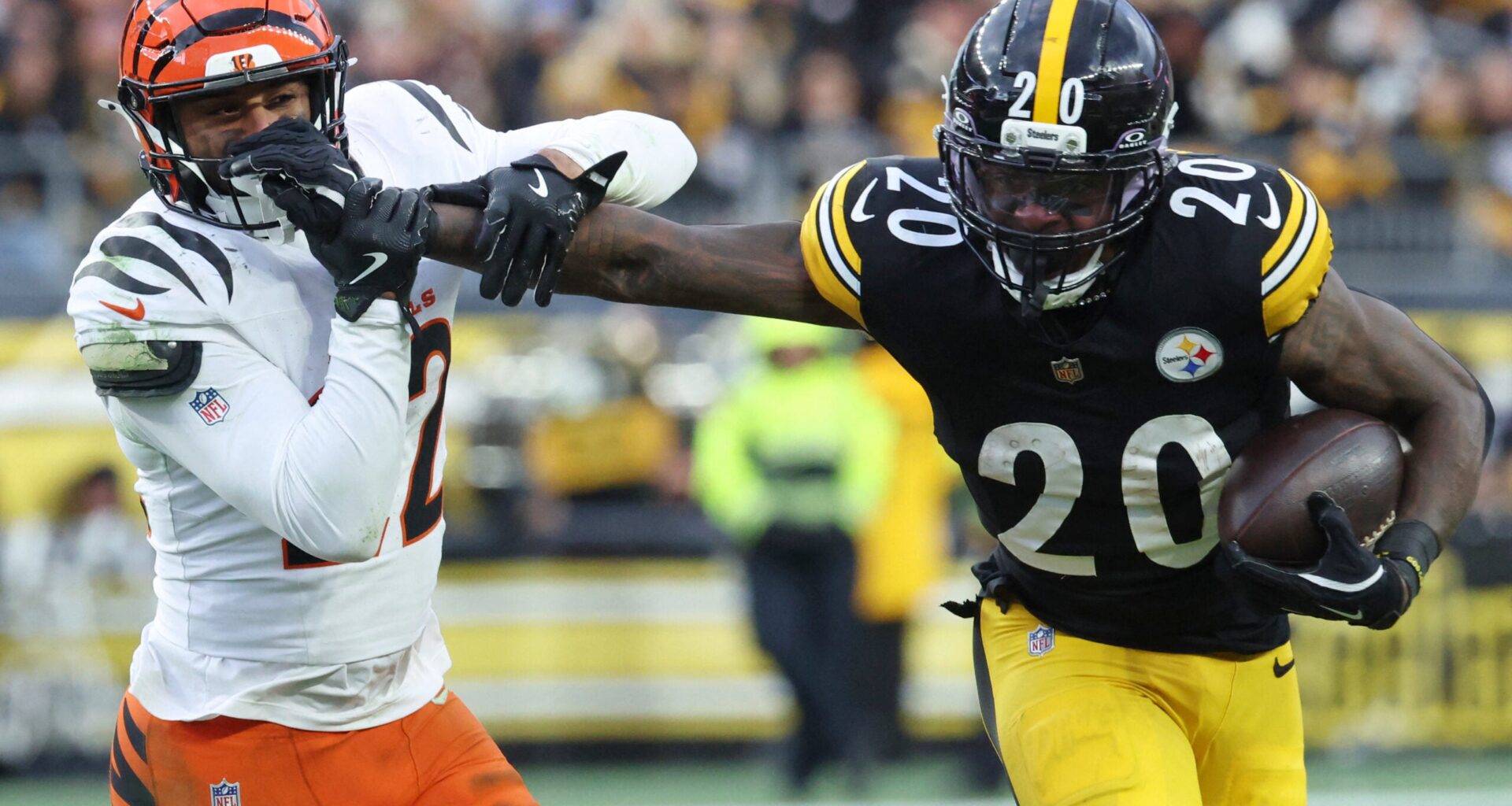 Nov 16, 2025; Pittsburgh, Pennsylvania, USA; Pittsburgh Steelers running back Kaleb Johnson (20) stiff arms Cincinnati Bengals safety Geno Stone (22) during the second half at Acrisure Stadium.