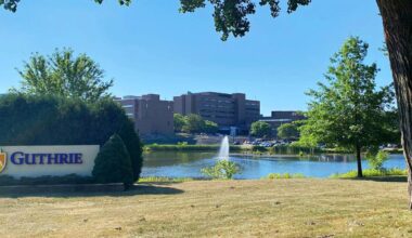 A health system campus framed by trees with a sign that says “Guthrie.” |