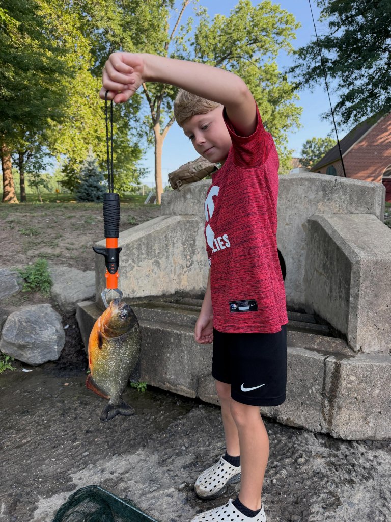 Young boy holding a fish with a gripper.