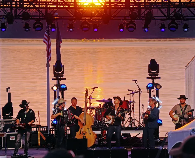 Old Crow Medicine Show band members perform as the sun sets behind the Rebich Investments Amphitheater and Presque Isle Bay in Erie, Pa., on Aug. 5, 2026.