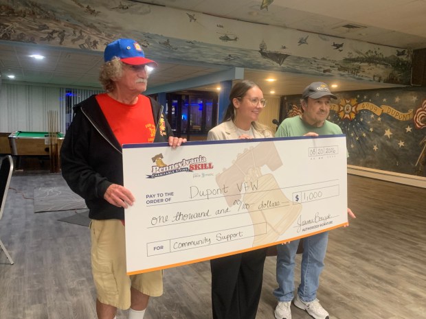 Rachel Albritton, the senior vice president of communication for Pace-O-Matic, center, presents a $1,000 check to Bob Lopata, the president and vice commander of the Dupont VFW, left; and Gary Kaspriskie, the Dupont VFW bar manager, right. (CHRISTOPHER DOYLE/STAFF PHOTO)