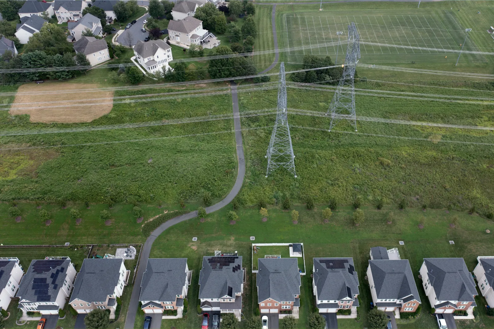 File photo: an aerial view shows power lines adjacent to homes near the construction of a new data center in Virginia on August 12, 2026.