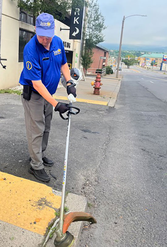A man trims weeds around a storm drain in Downtown Scranton, PA.