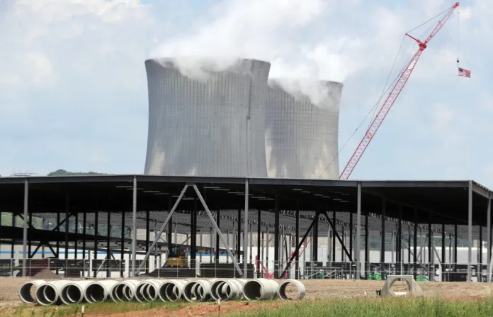 The cooling towers of a power plant loom over an Amazon Web Services data center construction project.