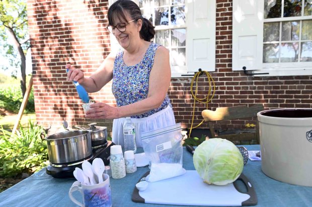 Debra Bauer of Fleetwood spoons out some homemade sauerkraut samples during the Pennsylvania German Farm Festival at the Historic Dreibelbis Farm, 356 Hard Hill Road near Virginville on Saturday, Aug. 23, 2025. (BILL UHRICH/READING EAGLE)