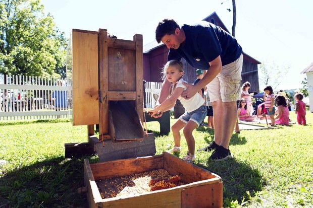 Aron Duncan of Kempton helps his daughter Emmy, 4, with a corn shucking crank during the Pennsylvania German Farm Festival at the Historic Dreibelbis Farm, 356 Hard Hill Road near Virginville on Saturday, Aug. 23, 2025. (BILL UHRICH/READING EAGLE)