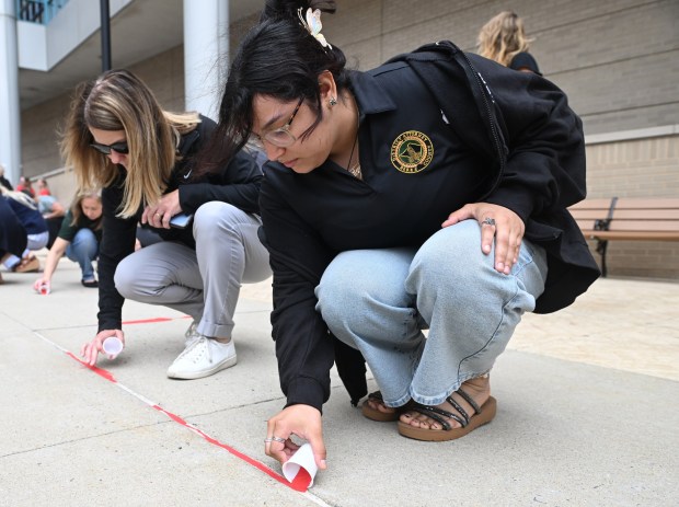 Melissa Miller, left, and Keren Mejica, both office support, pour red sand into sidewalk cracks during a red sand event at the Berks County Services Center to call attention to child trafficking on Thursday, July 30, 2026. (BILL UHRICH/READING EAGLE)