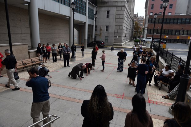 Red sand is poured in sidewalk cracks during an event at the Berks County Services Center to call attention to child trafficking on Thursday, July 30, 2026. (BILL UHRICH/READING EAGLE)
