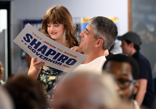 Jacob Socolar of Exeter Township holds up his daughter Isabele, 8, to see Gov. Josh Shapiro during a visit Saturday to the Berks County Democratic Committee, 1251 N. Front St. (BILL UHRICH/READING EAGLE)