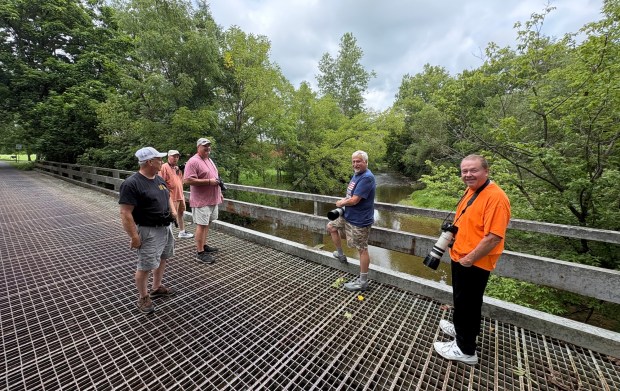 Birders stand on a bridge over the Saucony Creek in Richmond Township to catch a glimpse of the rare wood stork on Saturday. (BILL UHRICH/READING EAGLE)