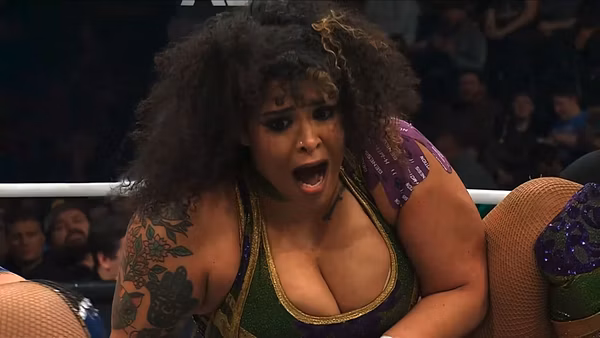 Willow Nightingale, the TBS Champion, appears shocked and intense during a wrestling match against Kamille at AEW Dynamite: Spring Breakthru. Her expressive face and detailed tattoos are visible as she engages in the competition.