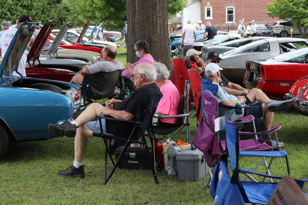 People relax in chairs between rows of cars Sunday, Aug. 2, 2026, at the 63rd annual Das Awkscht Fescht antique and classic car show at Macungie Memorial Park in Macungie. (Jon Chiu/The Morning Call)