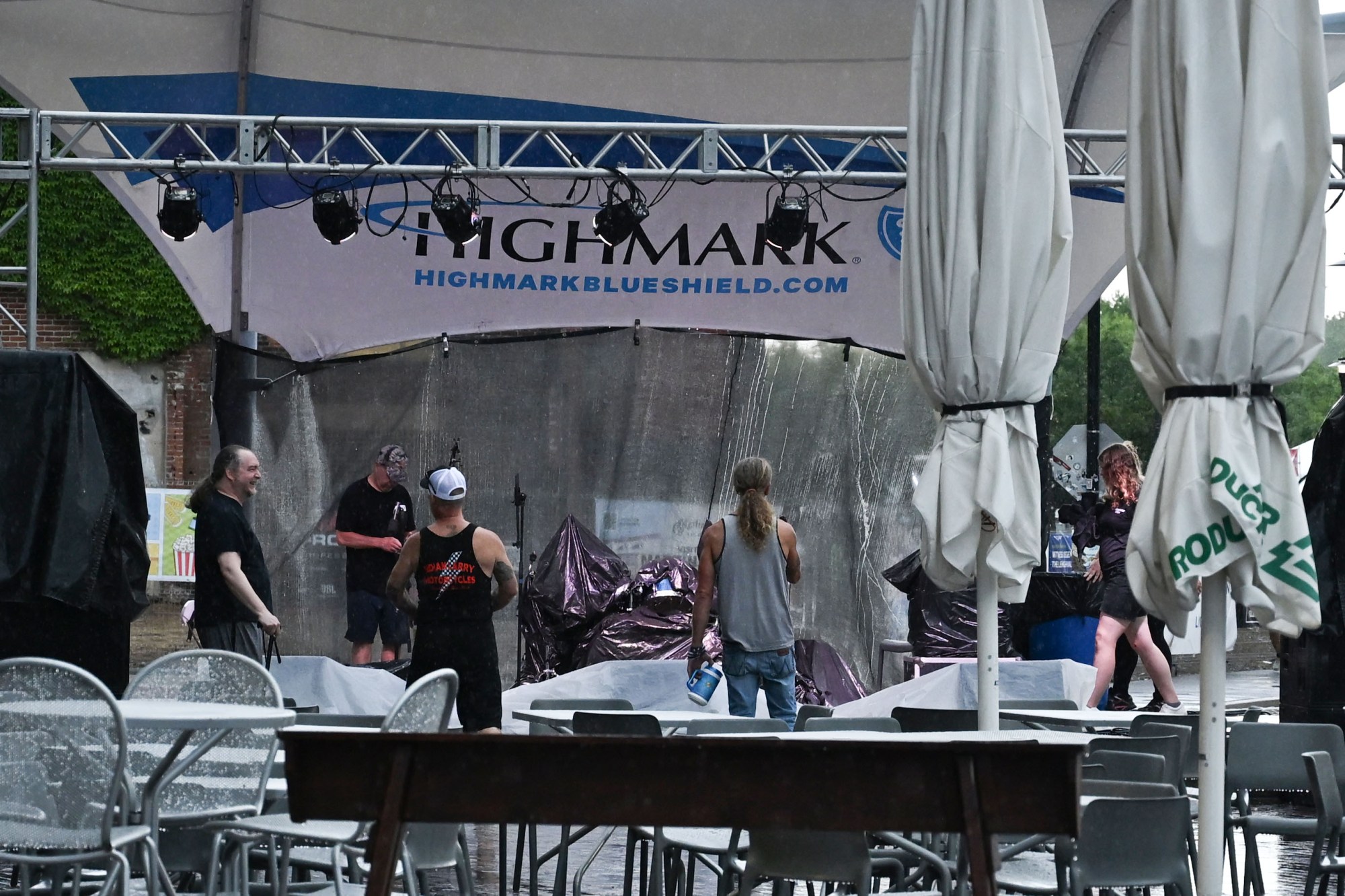 People remove plastic sheets used to protect musical instruments from a passing storm during Musikfest on Friday, Aug. 7, 2026, at the SteelStacks in Bethlehem. (Jon Chiu/The Morning Call)