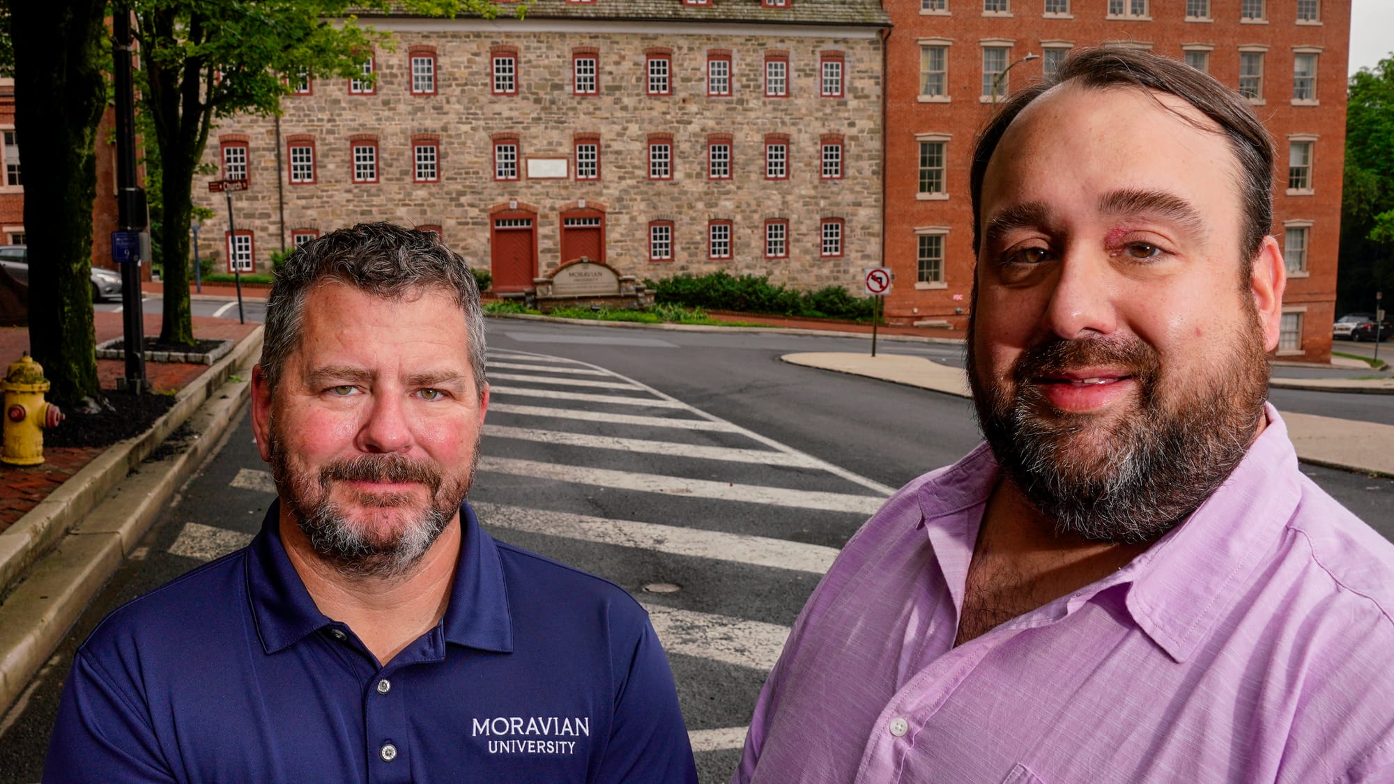 Moravian University representatives Michael Corr, left, and Mike Cook stand in front of the Brethren House which today is par