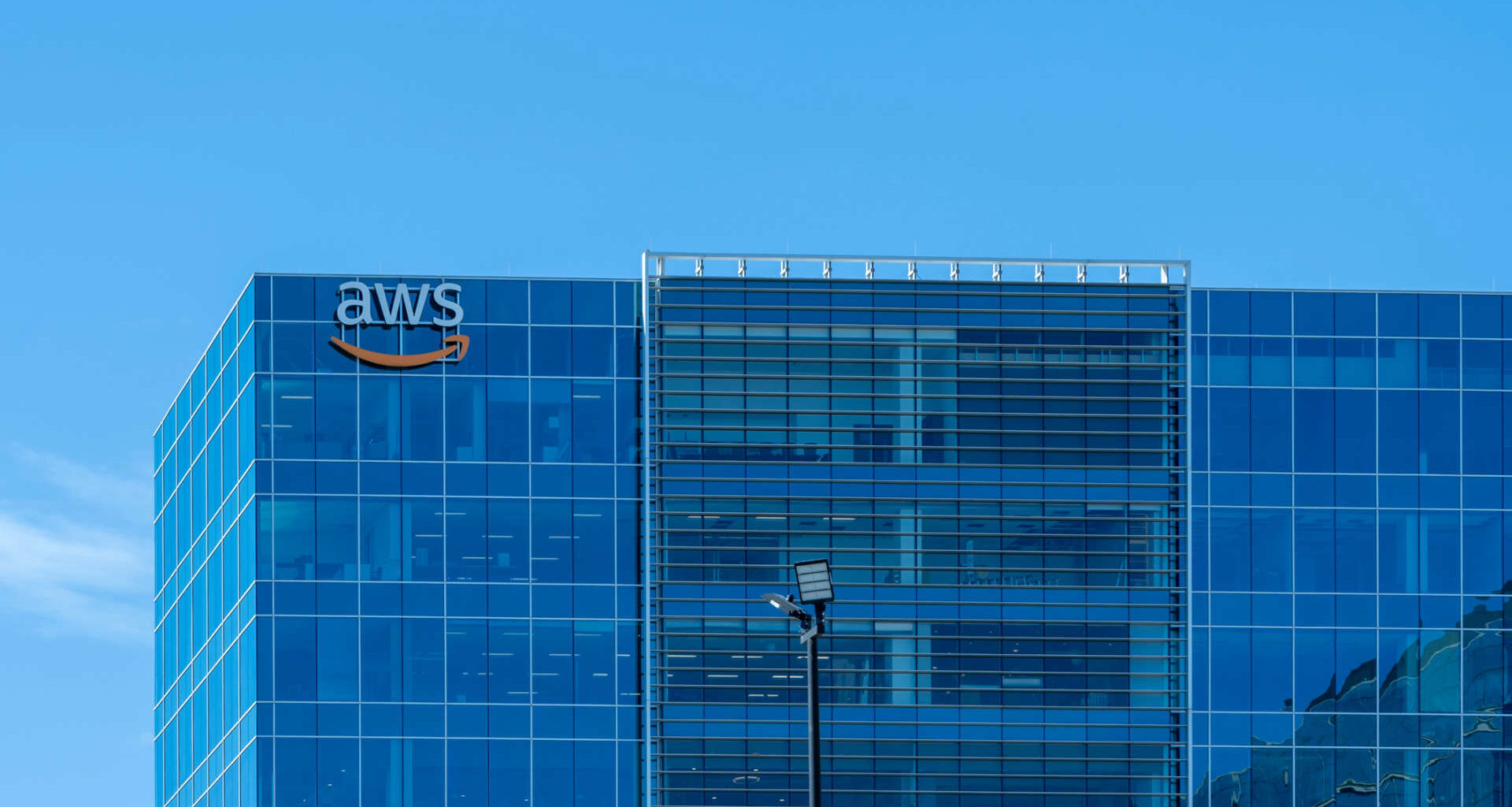 An office building with large glass windows and an AWS logo on the facade.