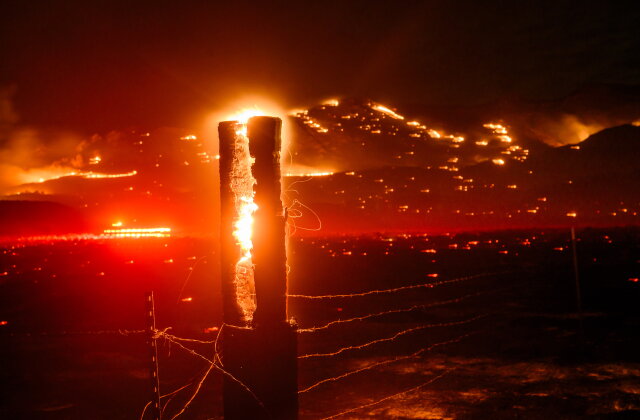 Seen in a long exposure, flames consume a fencepost as the Bug Fire burns near Doyle in unincorporated Lassen County, Calif., on Thursday, Aug. 13, 2026. (AP Photo/Noah Berger)