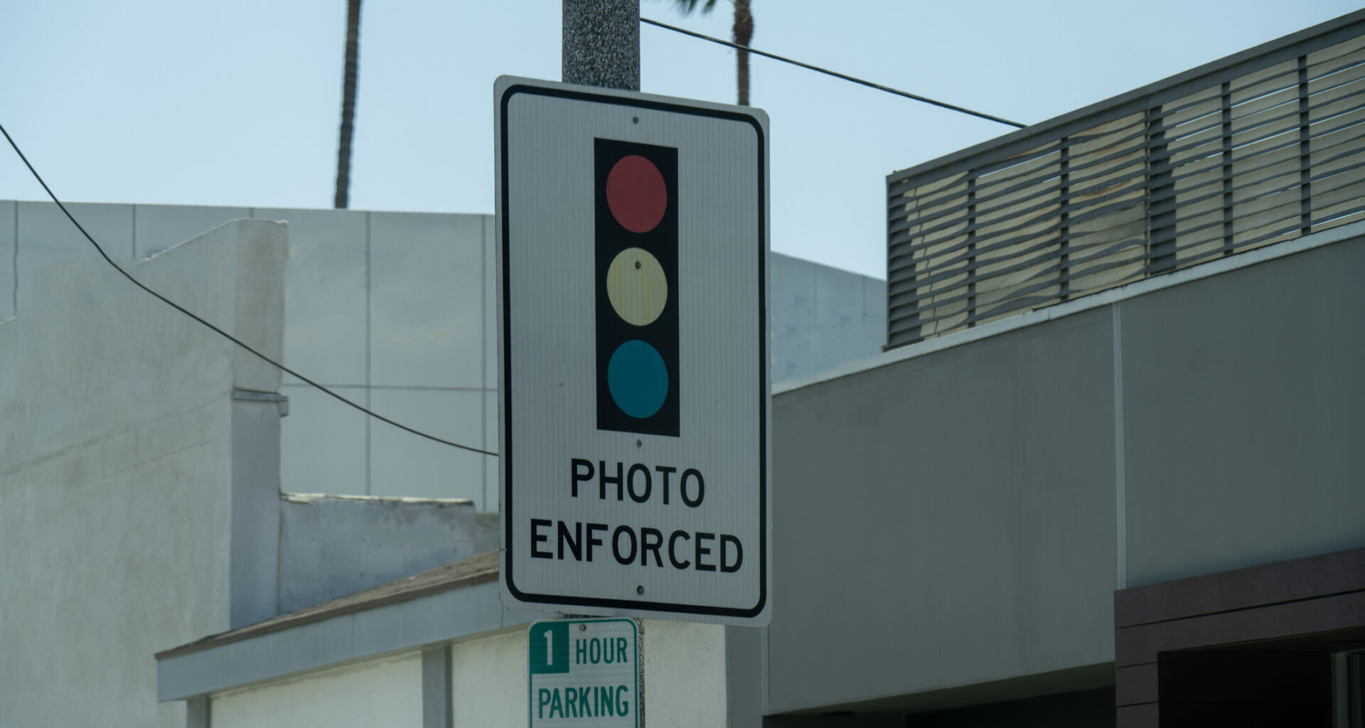 A traffic sign indicating "Photo Enforced" with red, yellow, and blue lights.
