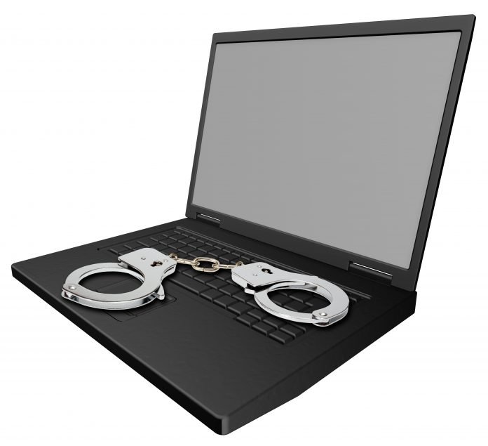 Laptop isolated on white with handcuffs.
