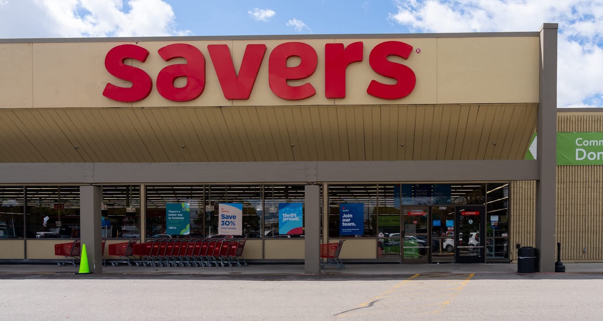 A storefront of a thrift store with red signage and shopping carts outside.