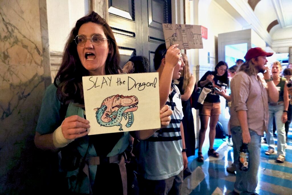 Protesters carry homemade signs during a rally at City Hall