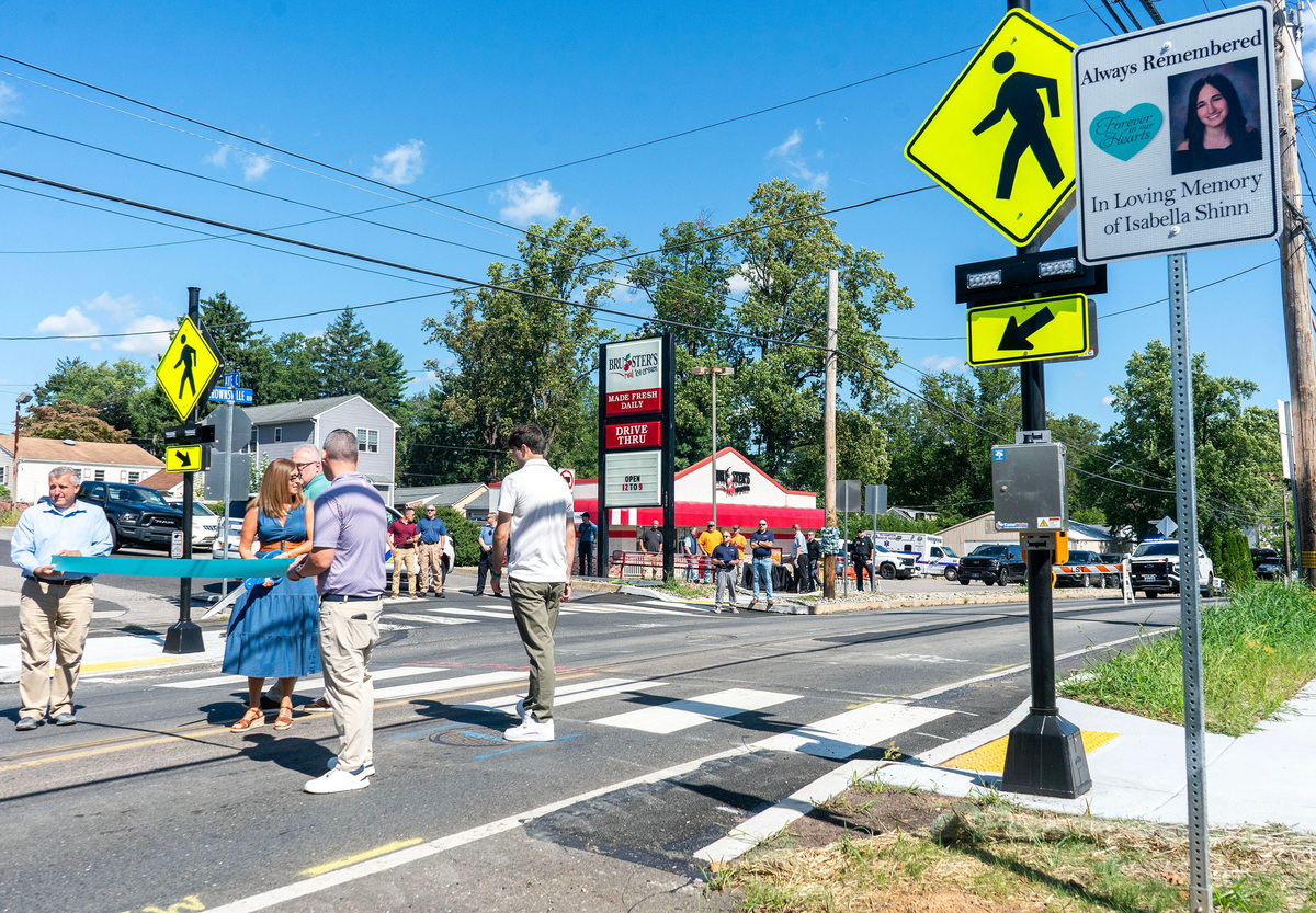 One of the two memorial signs near the crosswalk is unveiled during the ribbon cutting for the new crosswalk in Isabella Shinn’s honor on Brownsville Road near Avenue C in Feasterville on Sept. 15, 2026. Isabella Shinn was 18 when she was fatally injured crossing Brownsville Road after finishing her shift at Bruster's Ice Cream shop in December 6, 2022.