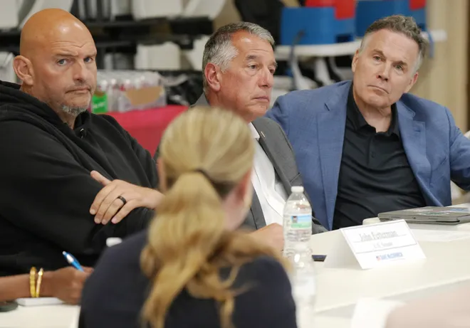 U.S. Senators John Fetterman, left, and Dave McCormick, right, flank Erie Insurance CEO Tim NeCastro during a roundtable discussion with community leaders dealing with housing, food insecurity and homelessness in Erie, Pa., on Aug. 28, 2026.