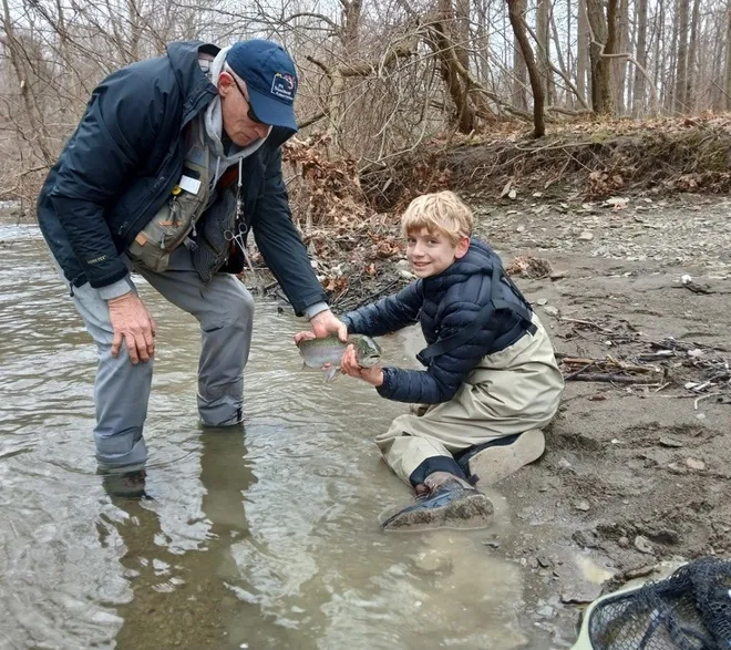 Chris Larson, president of the Pennsylvania Steelhead Association, helps his grandson, Ben, with a steelhead he caught.