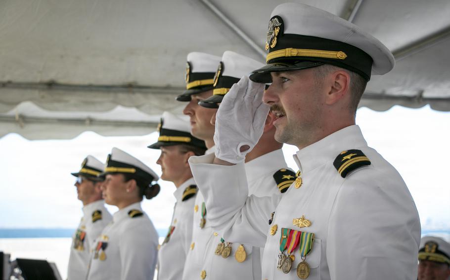 A sailor salutes while standing in formation.
