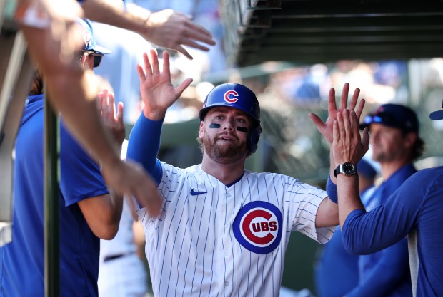 Cubs catcher Carson Kelly high-fives teammates in the dugout after scoring on a Seiya Suzuki single in the fourth inning against the Pirates on Sept. 11, 2026, at Wrigley Field. (Chris Sweda/Chicago Tribune)
