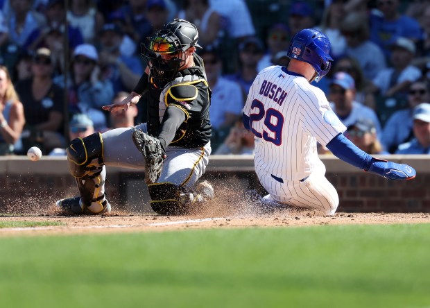 Pirates catcher Henry Davis tries to corral a throw to the plate as Cubs first baseman Michael Busch slides in safely at home in the sixth inning Friday, Sept. 11, 2026, at Wrigley Field. (Chris Sweda/Chicago Tribune)