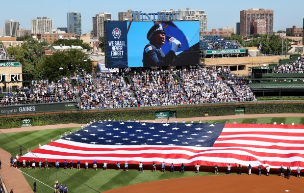On the 25th anniversary of the 9/11 terrorist attacks on the U.S., fans hold an American flag on the field before a Cubs-Pirates game on Sept. 11, 2026, at Wrigley Field. (Chris Sweda/Chicago Tribune)