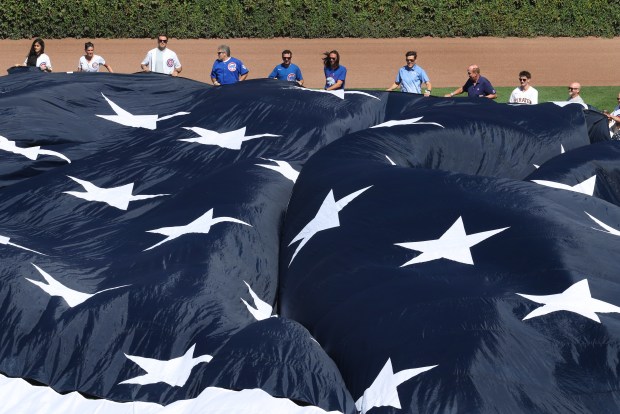 On the 25th anniversary of the 9/11 terrorist attacks, fans hold an American flag on the field before a Cubs-Pirates game Friday, Sept. 11, 2026, at Wrigley Field. (Chris Sweda/Chicago Tribune)