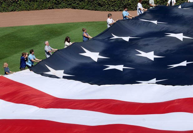 On the 25th anniversary of the September 11, 2001 terrorist attacks on the U.S., fans hold a U.S. flag on the field at Wrigley Field in Chicago before a game between the Chicago Cubs and the Pittsburgh Pirates. (Chris Sweda/Chicago Tribune)