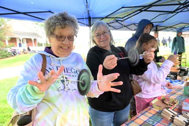 Elaine Brobst of Breinigsville, left, and Rosemary Falk of Krumsville try out spinners at an old-time toy display during the Heemet Fescht at the Pennsylvania German Cultural Heritage Center at Kutztown University on Saturday, Sept. 26, 2026. (BILL UHRICH/READING EAGLE)
