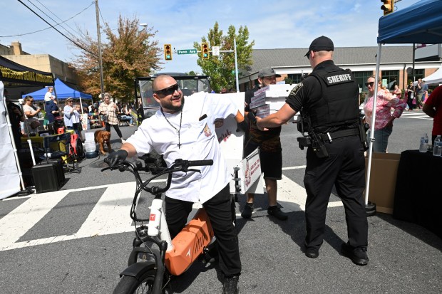 Chef David Calvo, left, and Doto Martinez make a pizza delivery to the law enforcement tent during the West Reading Fall Festival on Saturday, Sept. 19, 2026. . (BILL UHRICH/READING EAGLE)