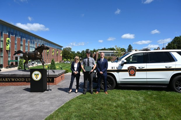 Pennsylvania State Police Trooper David Kuzmick, center, holds his degree from Marywood University, with President Lisa A. Lori, J.D., left, and Patrick Seffrin, Ph.D., Marywood Professor and Directorof its Center for Law, Justice and Policy, right. (COURTESY MARYWOOD UNIVERSITY)