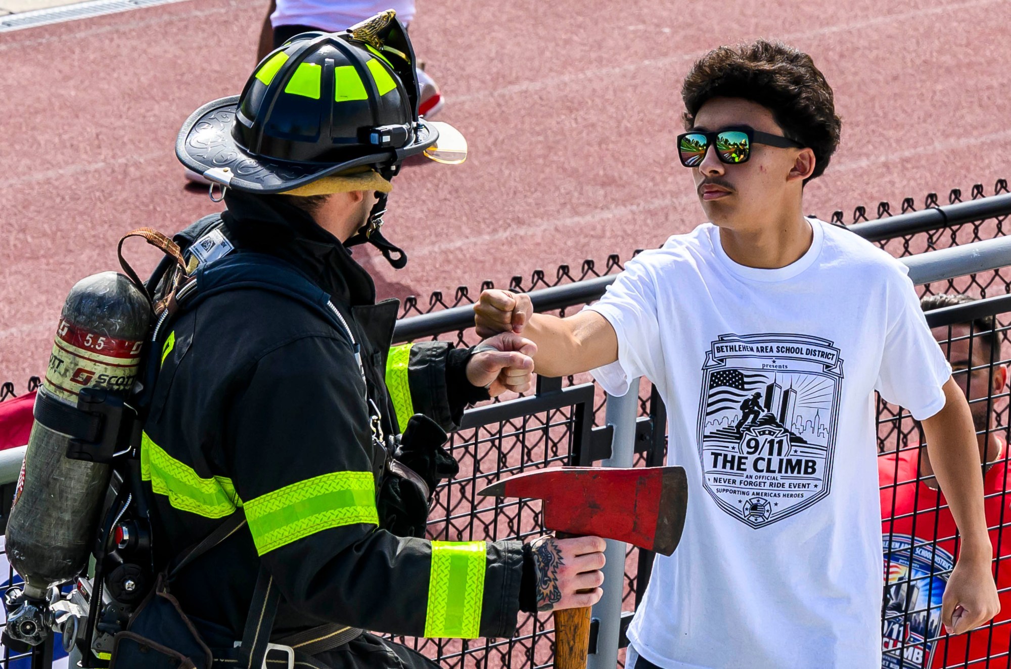 Liberty student Anthony Zappa greets Bethlehem firefighter Kyle Pochek wearing over 90 pounds of equipment before climbing the stadium stairs with Friday, Sept. 11, 2026, during "The Climb" event at BASD Stadium in Bethlehem. Bethlehem Area high school students, staff, first responders, military personnel and community partners came together for a student-centered 9/11 remembrance event in which students from Freedom and Liberty High Schools climbed the stadium steps, walked the track and engaged in other activities to remember the lives lost 25 years ago. The goal was to climb 2,200 stairs or walk three miles, symbolizing 110 flights of stairs in one of the World Trade Center towers.(April Gamiz/The Morning Call)