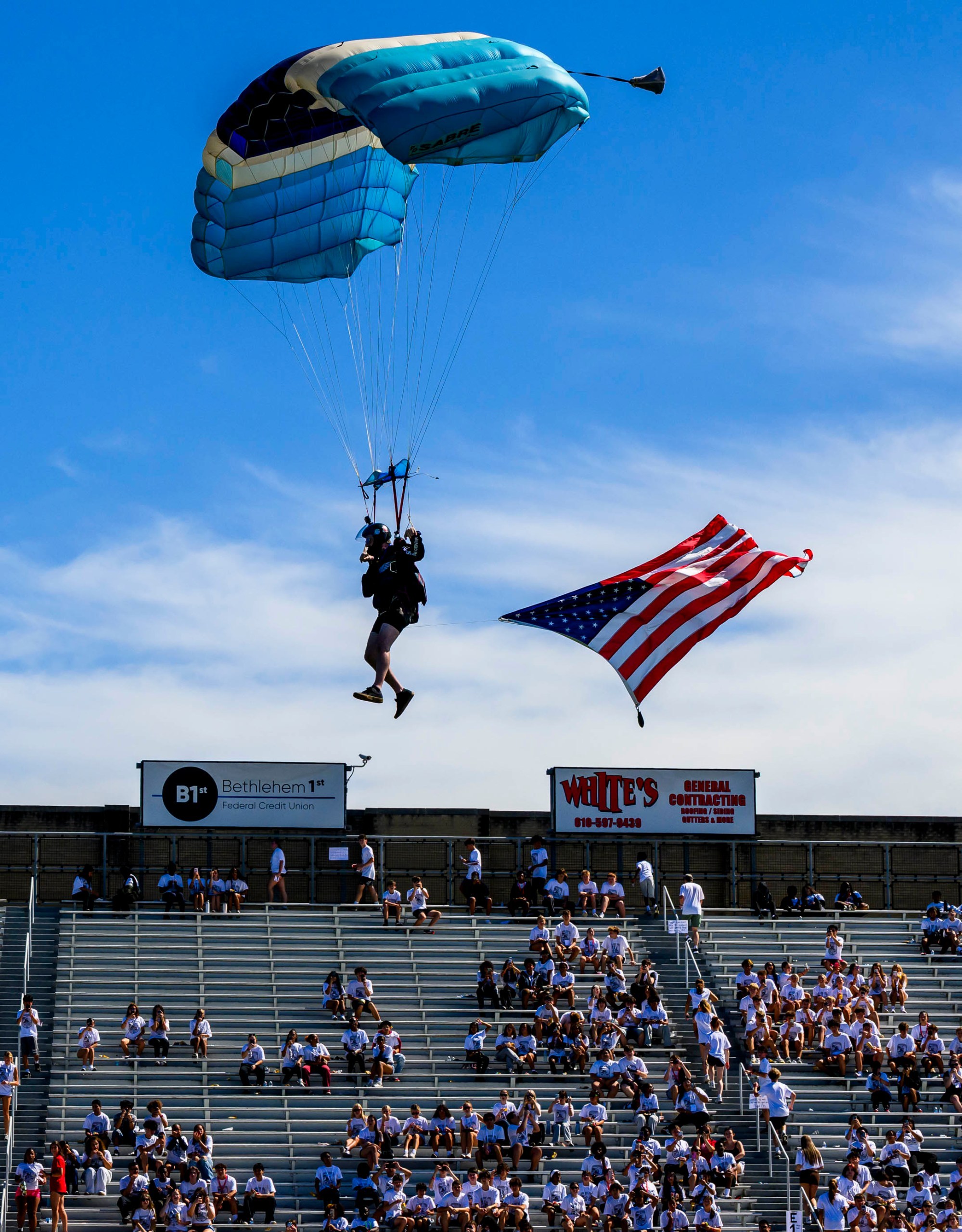 Pegasus parachuter Tom Carbone lands with an American flag Friday, Sept. 11, 2026, during "The Climb" event at BASD Stadium in Bethlehem. Bethlehem Area high school students, staff, first responders, military personnel and community partners came together for a student-centered 9/11 remembrance event in which students from Freedom and Liberty High Schools climbed the stadium steps, walked the track and engaged in other activities to remember the lives lost 25 years ago. The goal was to climb 2,200 stairs or walk three miles, symbolizing 110 flights of stairs in one of the World Trade Center towers.(April Gamiz/The Morning Call)