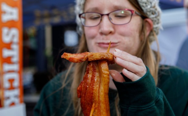 Kara Plesic of Steelton enjoys bacon-on-a-stick during BaconFest on Saturday, Nov. 1, 2025, at Centre Square in Easton. The festival which features music, family-friendly fun and, of course, bacon, continues Sunday. (Jane Therese/Special to The Morning Call)