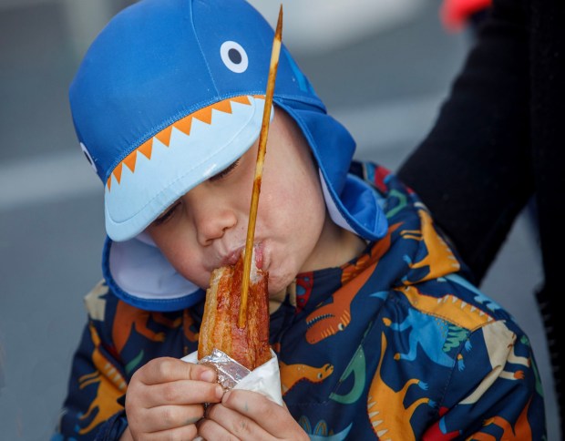 John Rossi, 4, of Stroudsburg enjoys bacon-on-a-stick from Greek Street in Allentown during BaconFest on Saturday, Nov. 1, 2025, at Centre Square in Easton. The festival which features music, family-friendly fun and, of course, bacon, continues Sunday. (Jane Therese/Special to The Morning Call)