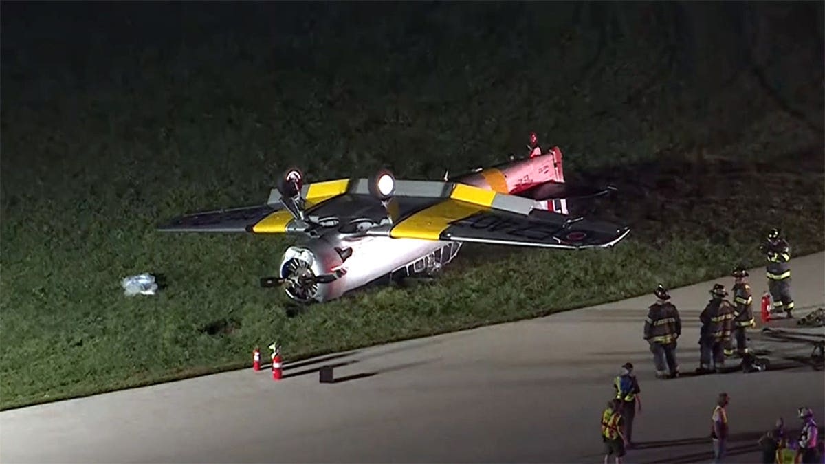 first responders stand near the overturned aircraft