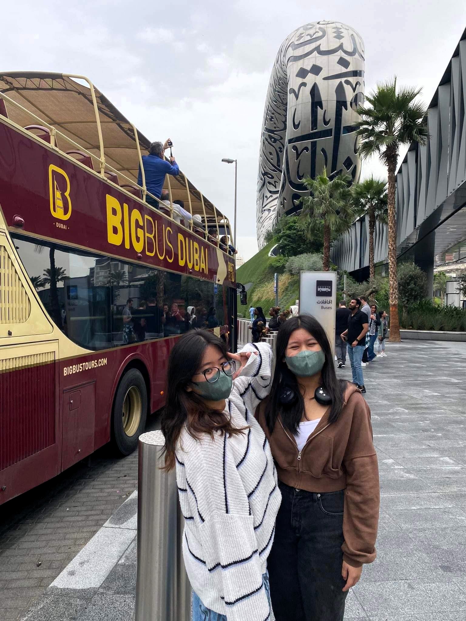 Two women standing outside a bus and museum