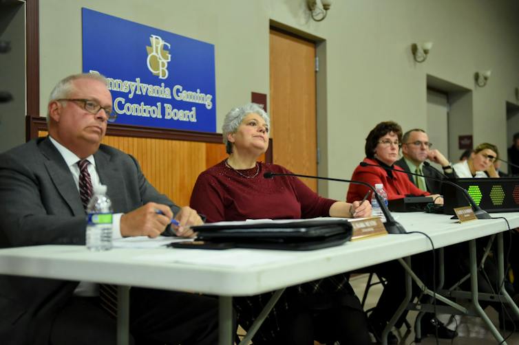 Five people sit in front of a sign that reads