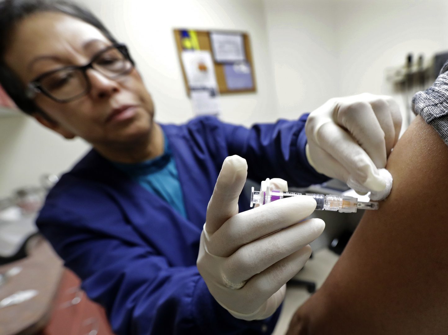 FILE PHOTO: Ana Martinez, a medical assistant at the Sea Mar Community Health Center, gives a patient a flu shot, Thursday, Jan. 11, 2018 in Seattle.  