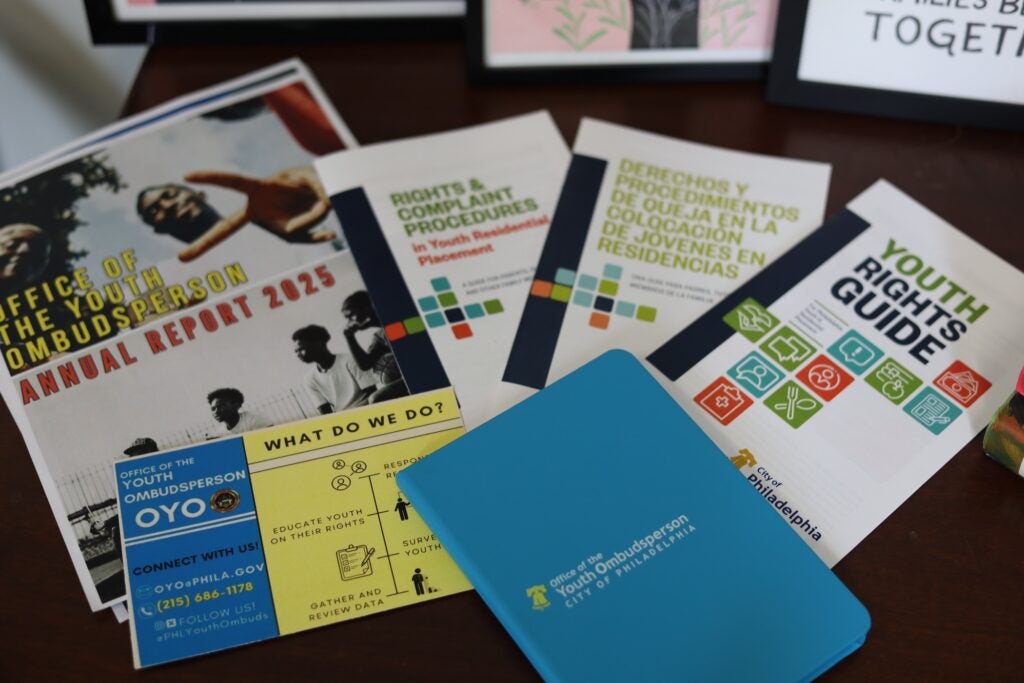 Pamphlets and fliers are displayed on a table with information from the Office of the Youth Ombudsperson.